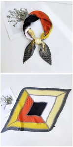 Detail of pleated silk scarf with orange and grey chain print on a white background