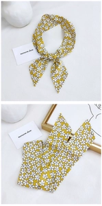 Detail of yellow floral cotton linen scarf tied in a bow on a bright white background