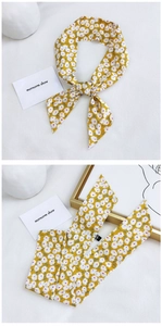 Detail of yellow floral skinny scarf featuring white daisy prints and soft cotton texture
