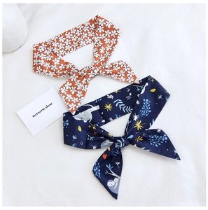 Detail of cotton linen hair ties with orange floral and blue koala patterns on white fabric