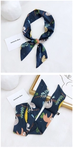 Detail of navy blue silk scarf with sloth and leaf pattern used as head or neck tie