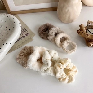 Dettaglio del set di 7 elastici in peluche dai toni caldi della terra su tavolo bianco