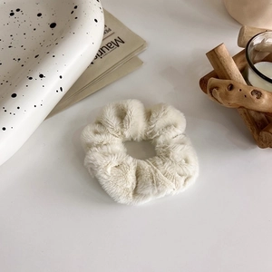 Dettaglio di un elastico per capelli in morbido peluche crema con trama in ecopelliccia