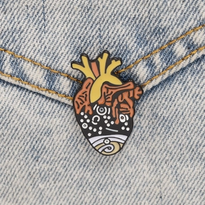Close-up of anatomical heart enamel pin on denim fabric showing artistic details