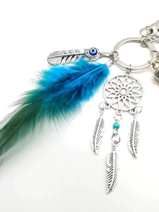 Close-up of bohemian dreamcatcher charm with blue gradient feathers and evil eye bead