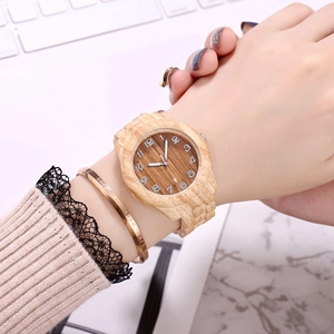 Macro view of a creative bamboo grain wooden watch on wrist with a gold bracelet