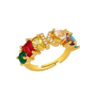 Macro shot of gold letter K ring with colorful cubic zirconia and diamond-encrusted letter