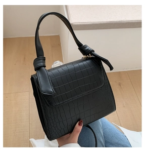 Detail shot of black crocodile texture handbag with unique knotted handle design