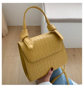 Detailed close-up of yellow crocodile texture leather bag with decorative handle knot