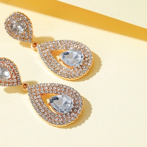 Detailed close-up of luxury gold teardrop earrings with shimmering crystal pavé setting