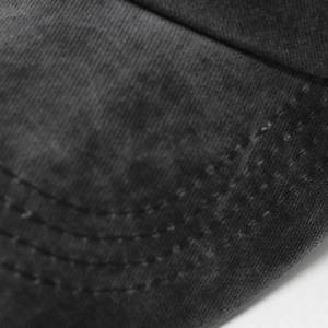 Macro shot of washed cotton twill fabric and reinforced stitching on a grey baseball cap