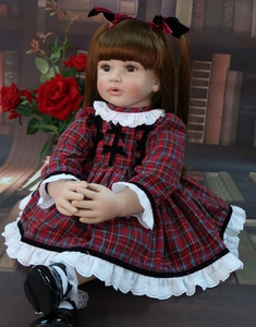 Detailed view of reborn toddler doll in red plaid dress seated in a library scene