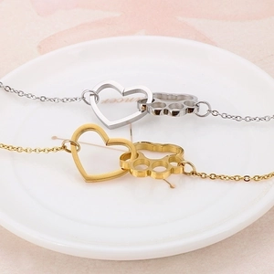 Gold and silver heart paw print stainless steel bracelets on a white ceramic plate
