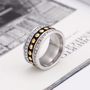 Silver wide ring with gold dots and zircon accents on a magazine background