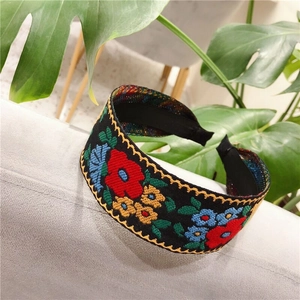 Detail of embroidered floral headband with colorful patterns on black wide band
