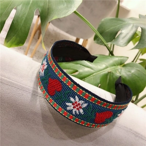 Detail of navy blue wide headband featuring ethnic floral embroidery and heart patterns