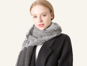 Detail of soft grey plaid winter scarf with thick texture and tassel fringe shown on model