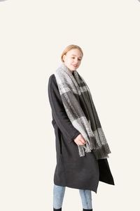 Detail of grey plaid fringe scarf styled with a long black wool coat on model