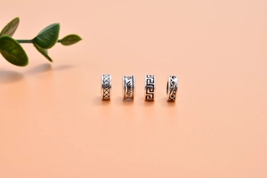 Macro shot of four vintage S925 sterling silver spacer beads with intricate relief patterns
