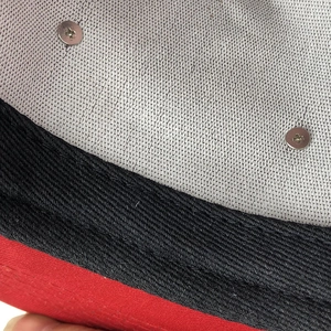 Macro detail of red cap interior featuring reinforced metal rivets and twill weaving