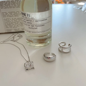 Modern 925 sterling silver H ring and textured square pendant on a minimalist white desk