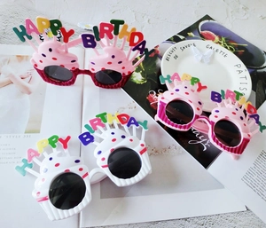 Close-up of pink and white cupcake-shaped Happy Birthday sunglasses in flat lay style