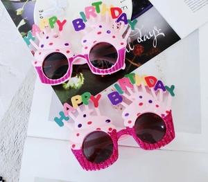 Detail view of pink cupcake birthday party glasses with colorful happy birthday letters