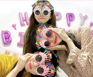 Three female models wearing colorful Happy Birthday cake party glasses in a festive setting
