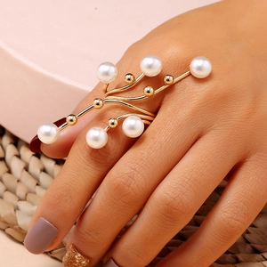 Detailed view of creative branch-shaped gold ring with multiple pearls on model finger