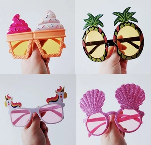 Detail showing colorful ice cream, pineapple, and unicorn party sunglasses held in hand