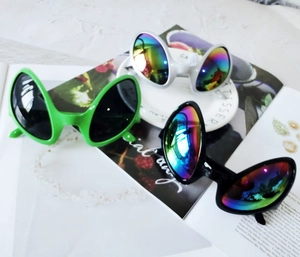 Funny alien sunglasses with green, white, black frames and rainbow lenses on magazine