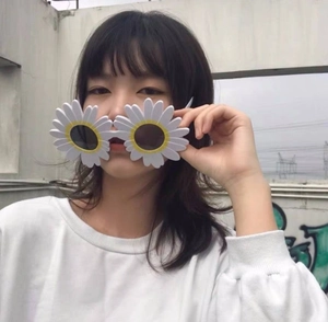 Close-up of white daisy sunglasses with yellow centers and black lenses worn by a model