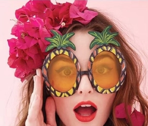 Detail of pineapple party sunglasses with yellow lenses and green leaf frames on a model