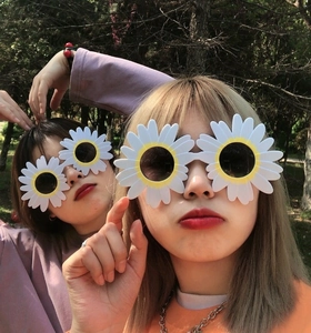 Funny daisy shaped sunglasses with white petals and yellow frames on female models outdoors