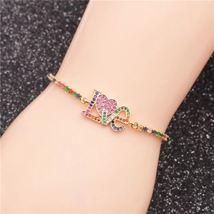 Dettaglio del bracciale LOVE a cuore dorato con zirconi colorati indossato