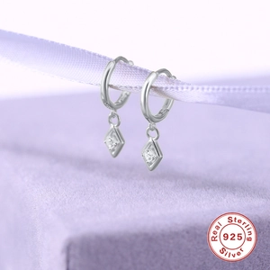 Macro shot of S925 sterling silver diamond-shaped earrings on a purple ribbon