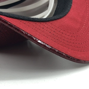Dettaglio del cappuccio in tela rossa con bordo in pelle coccodrillo e cuciture fini