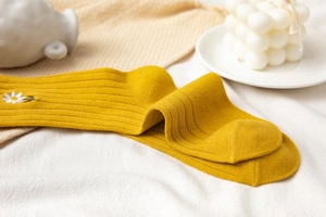 Detail of yellow cotton mid-calf socks with delicate daisy embroidery and ribbed texture