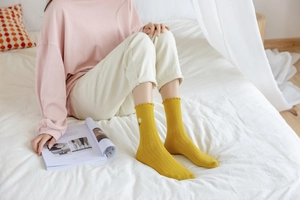 Detail of ginger yellow crew socks featuring ruffle cuffs and white daisy embroidery