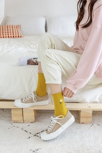 Detail of yellow cotton ruffle socks featuring white daisy embroidery with canvas shoes