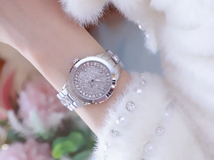 Detail of luxury women's watch with full crystal pavé dial and silver steel band