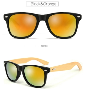 Detail view of black sunglasses with orange reflective lenses and natural bamboo temples