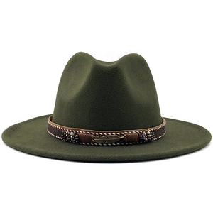 Detail of dark green fedora hat featuring ethnic woven band and bronze feather pendant