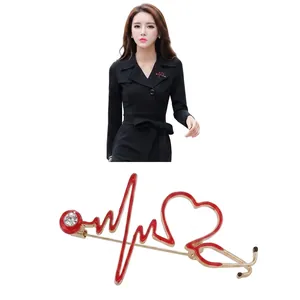 Detail of a gold stethoscope heart brooch with red enamel and a white crystal on a model