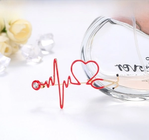 Close-up of stethoscope heart brooch with red enamel and sparkling rhinestone detail
