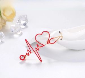 Macro detail of stethoscope heart brooch with red enamel and a sparkling rhinestone