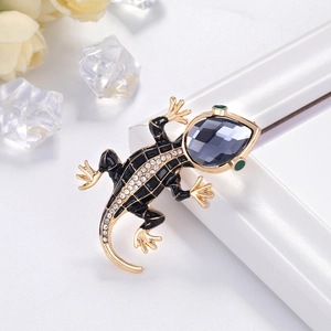 Golden lizard brooch with black enamel and sparkling rhinestones on a white background