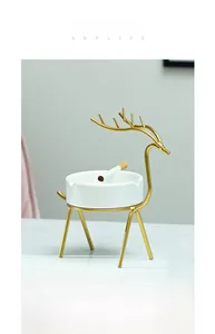 Détail du support en métal doré de cerf nordique avec un cendrier rond en céramique blanche