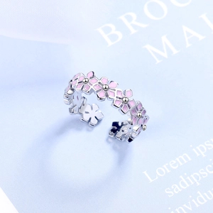 Elegant silver open ring featuring pink floral leaf designs on a soft blue background