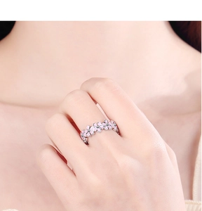 Close-up of a silver ring with pink flower patterns on a model's ring finger